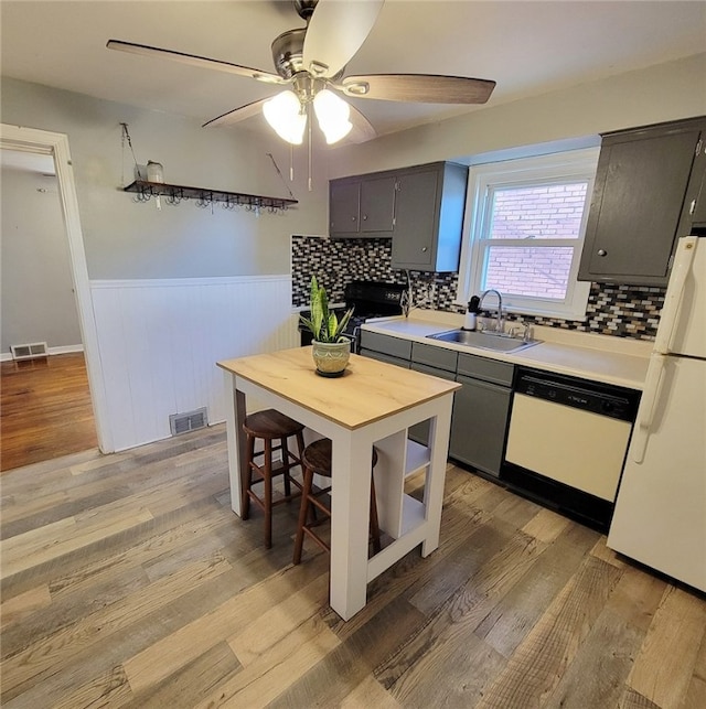 kitchen featuring white appliances, sink, light hardwood / wood-style flooring, and tasteful backsplash