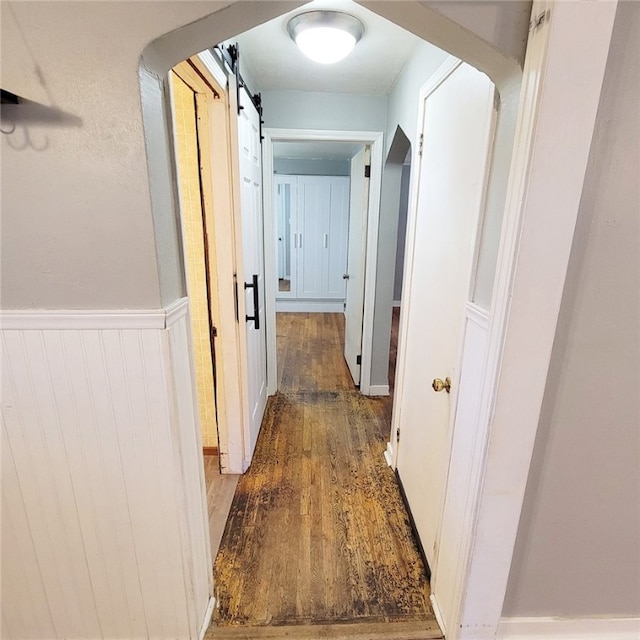 hall with wooden walls, hardwood / wood-style flooring, and a barn door