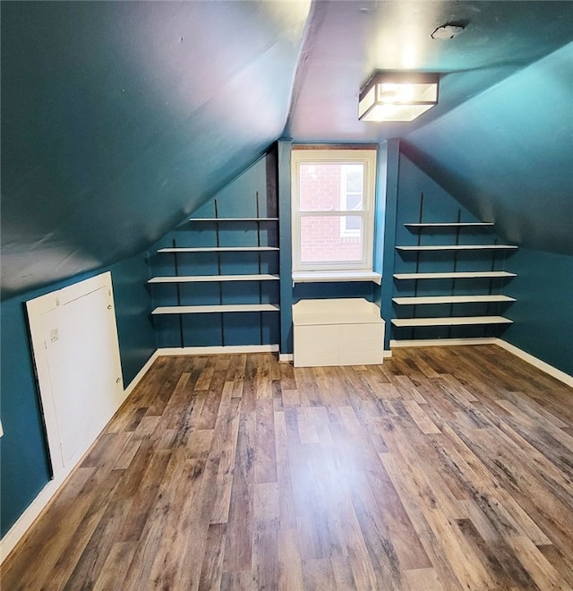 additional living space with wood-type flooring and vaulted ceiling