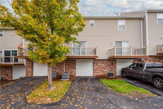 rear view of property with cooling unit, a balcony, and a garage