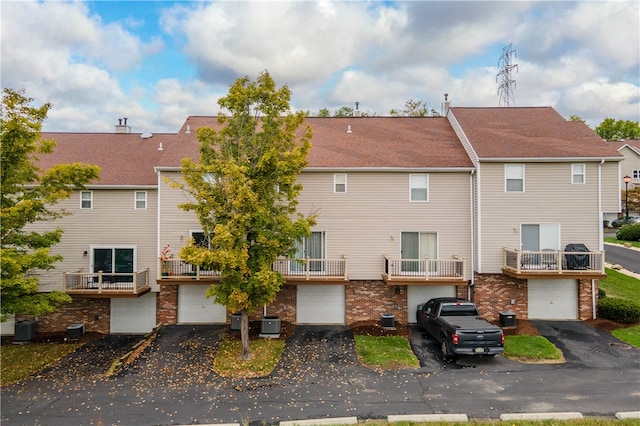 rear view of property with a balcony, a garage, and central air condition unit