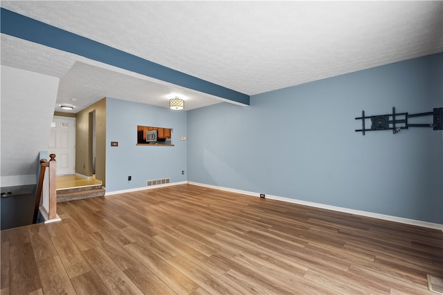 unfurnished living room featuring a textured ceiling and hardwood / wood-style floors