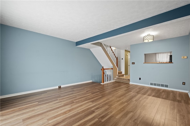 unfurnished living room with wood-type flooring and a textured ceiling