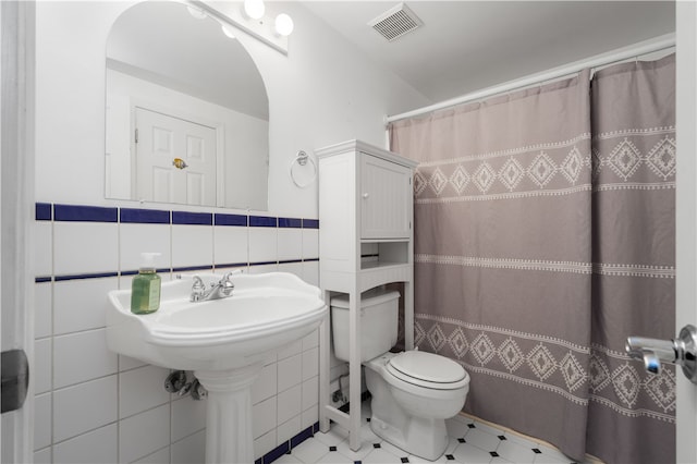 bathroom with tile walls, a shower with curtain, tile patterned floors, and toilet