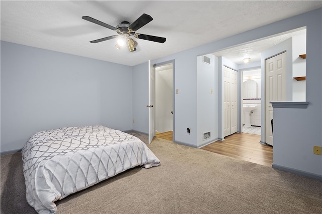 bedroom with ceiling fan, a textured ceiling, light hardwood / wood-style floors, and ensuite bathroom