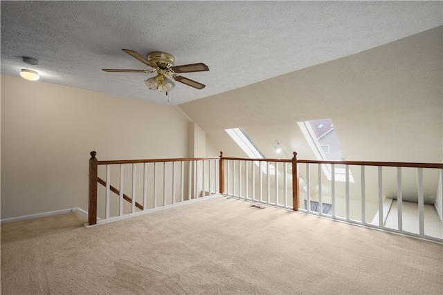 additional living space featuring ceiling fan, a textured ceiling, vaulted ceiling with skylight, and carpet