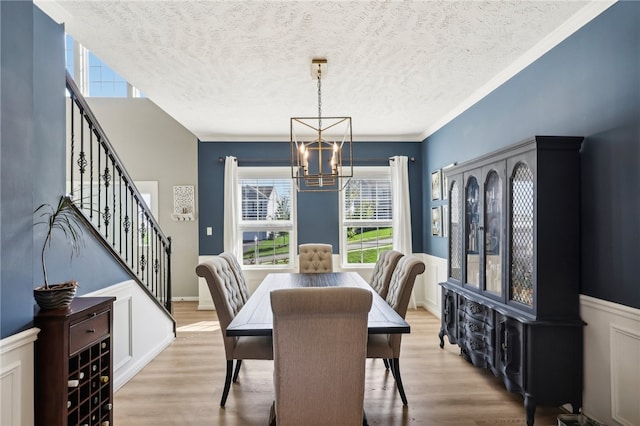 dining area with an inviting chandelier, light hardwood / wood-style floors, crown molding, and a textured ceiling