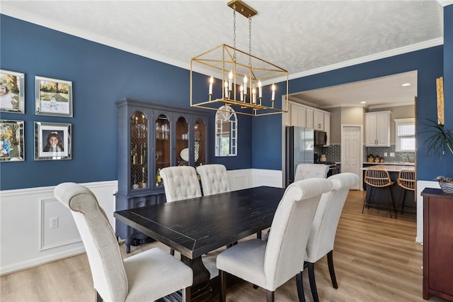 dining room with a notable chandelier, crown molding, and light hardwood / wood-style floors