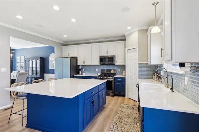 kitchen featuring blue cabinets, white cabinets, a kitchen island, appliances with stainless steel finishes, and light hardwood / wood-style floors