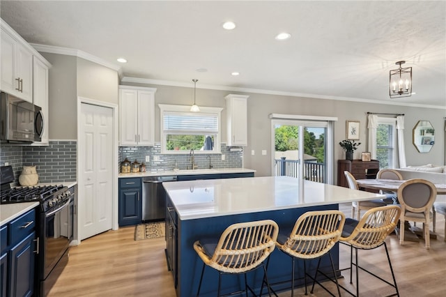 kitchen featuring plenty of natural light, stainless steel appliances, blue cabinets, and white cabinetry