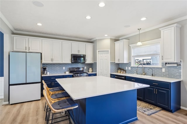 kitchen featuring white cabinets, hanging light fixtures, a kitchen island, appliances with stainless steel finishes, and blue cabinetry