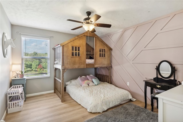 bedroom with light wood-type flooring, ceiling fan, and a textured ceiling