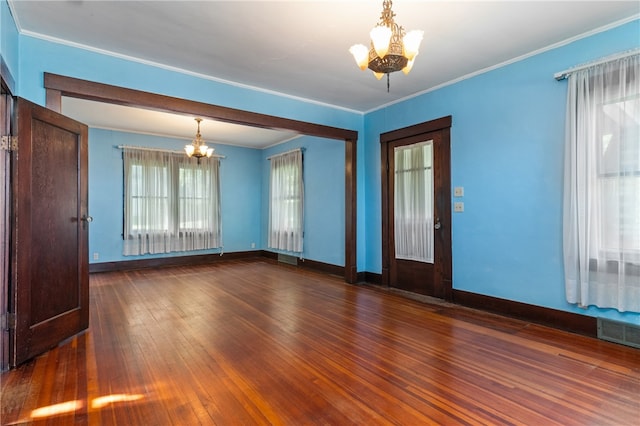 empty room with ornamental molding, dark wood-type flooring, and an inviting chandelier