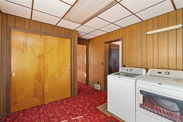 laundry room with washing machine and dryer, dark carpet, and wooden walls