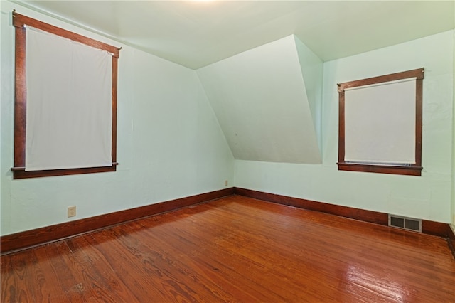 additional living space with hardwood / wood-style flooring and lofted ceiling