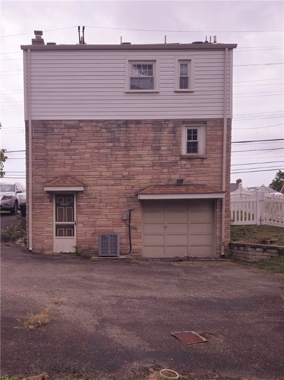 back of property featuring a garage and central AC