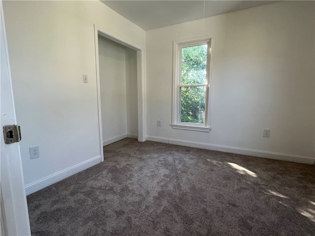 unfurnished room featuring dark colored carpet