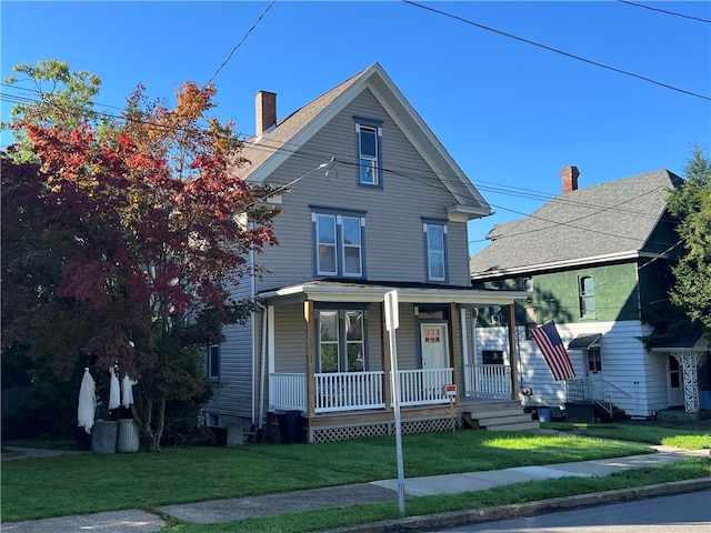 view of property featuring covered porch and a front yard