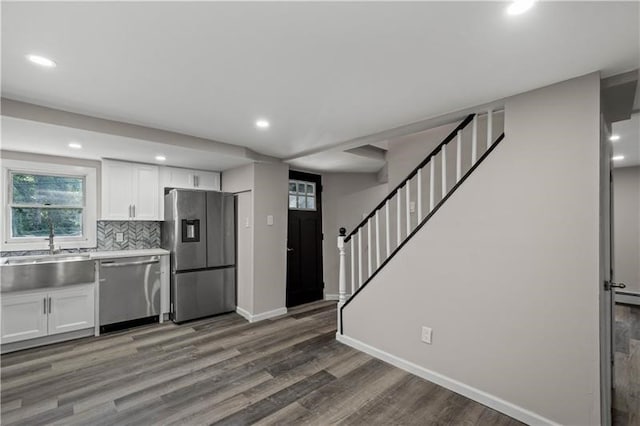 kitchen with dark wood-type flooring, sink, white cabinetry, backsplash, and appliances with stainless steel finishes