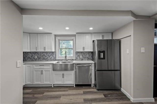 kitchen featuring dark hardwood / wood-style floors, sink, white cabinetry, stainless steel appliances, and backsplash