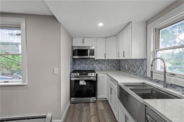 kitchen featuring white cabinets, sink, dark wood-type flooring, appliances with stainless steel finishes, and a baseboard radiator