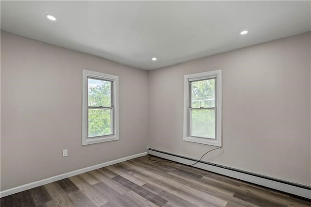 unfurnished room with light wood-type flooring, baseboard heating, and a wealth of natural light