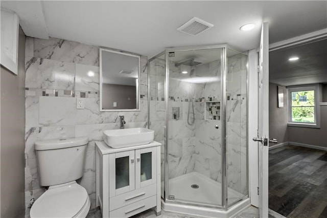 bathroom with vanity, wood-type flooring, tile walls, toilet, and a shower with door