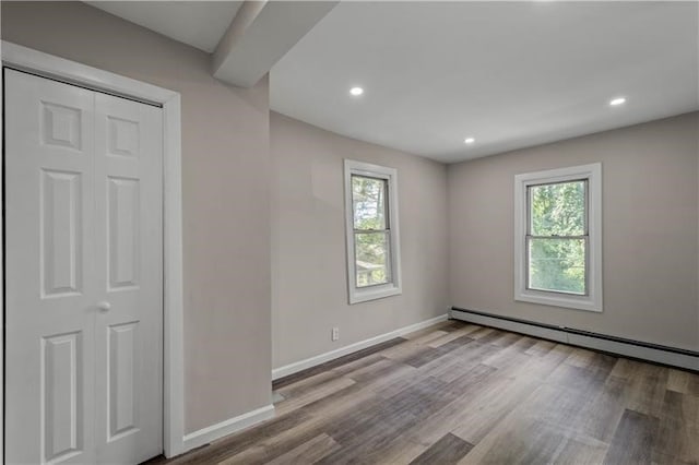 spare room featuring light hardwood / wood-style flooring, a baseboard heating unit, and plenty of natural light