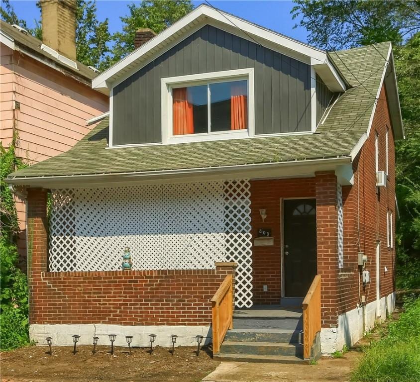 view of front of home with brick siding and roof with shingles