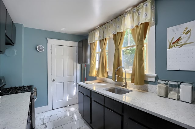 kitchen featuring light stone countertops, sink, and stainless steel range oven