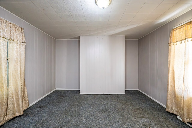 carpeted empty room featuring wooden walls