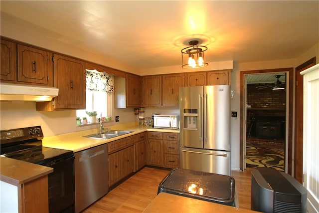 kitchen with appliances with stainless steel finishes, sink, and light hardwood / wood-style flooring