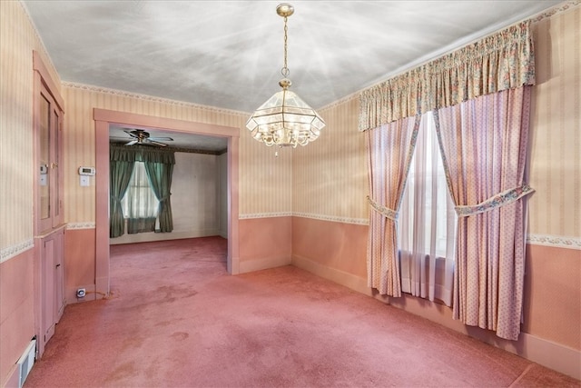 carpeted empty room featuring ceiling fan with notable chandelier and ornamental molding