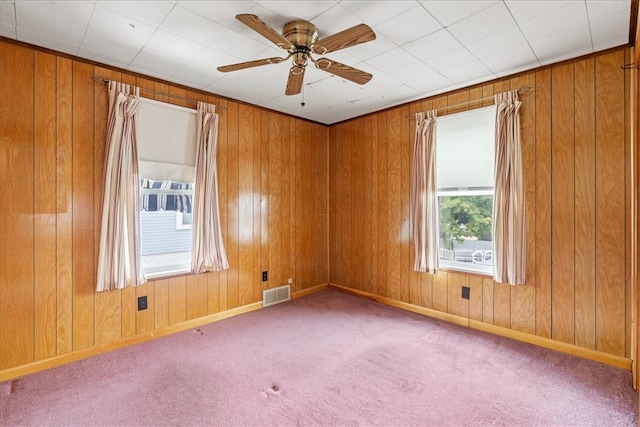 carpeted empty room featuring ceiling fan and wooden walls