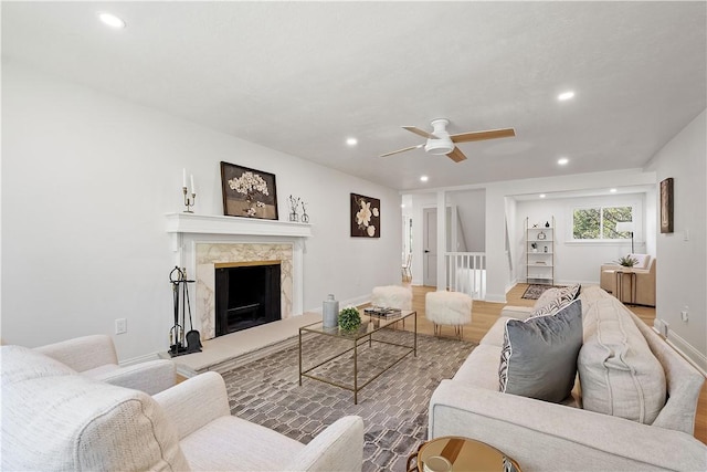 living room with a premium fireplace, ceiling fan, and hardwood / wood-style flooring