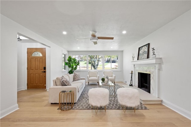 living room featuring ceiling fan, light wood-type flooring, and a premium fireplace