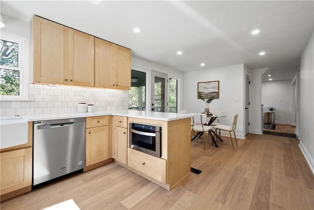 kitchen featuring kitchen peninsula, light hardwood / wood-style flooring, light brown cabinets, and appliances with stainless steel finishes