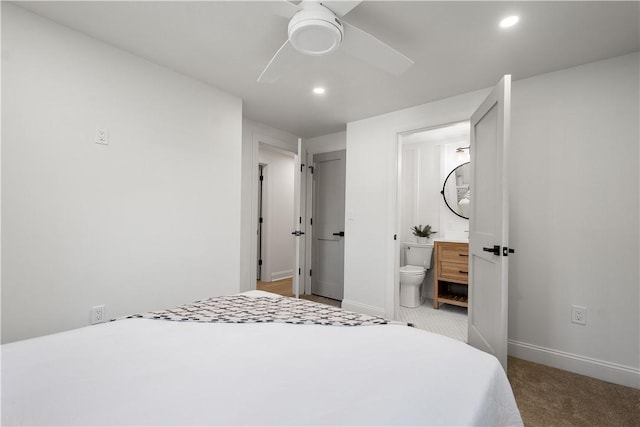 bedroom featuring light carpet, ensuite bathroom, and ceiling fan