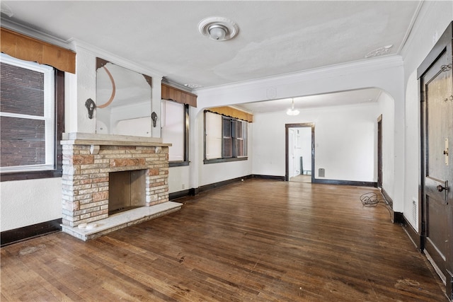 unfurnished living room featuring a stone fireplace, ornamental molding, and dark hardwood / wood-style flooring