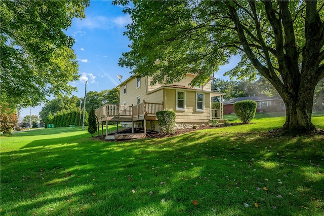 rear view of house featuring a wooden deck and a yard