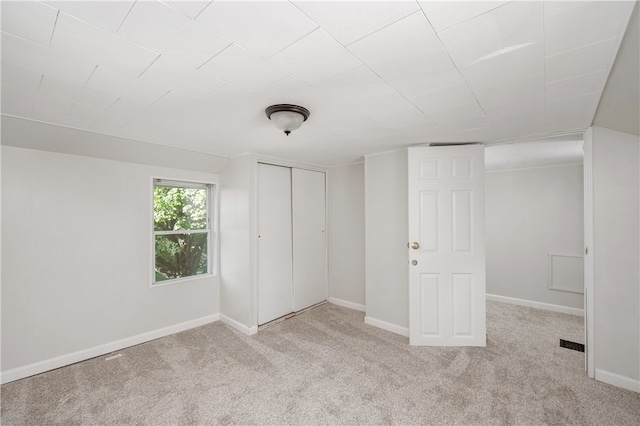 unfurnished bedroom featuring light colored carpet and a closet