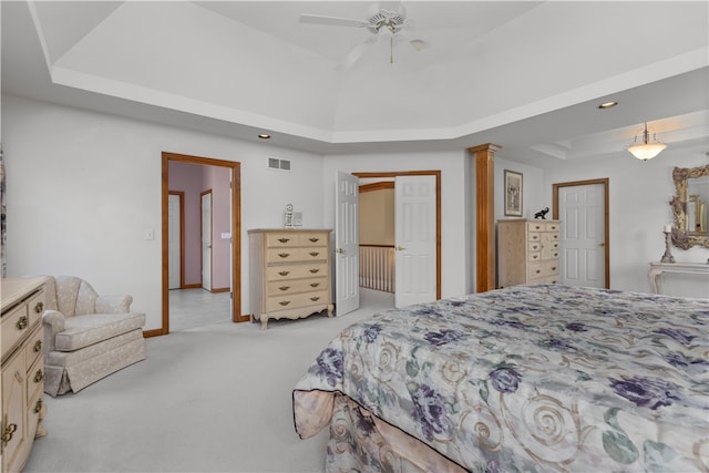 bedroom with a tray ceiling, light carpet, and ceiling fan