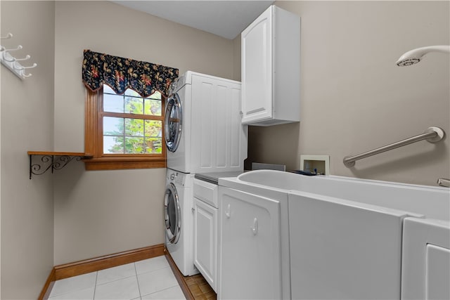 washroom featuring light tile patterned floors, cabinets, and stacked washer / drying machine