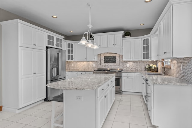 kitchen featuring decorative backsplash, white cabinetry, high end appliances, a kitchen island, and sink