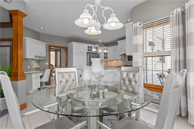 dining area featuring light tile patterned floors, decorative columns, and a chandelier