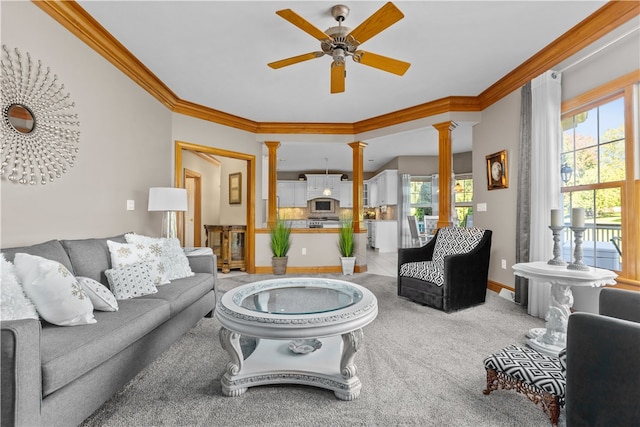 living room with decorative columns, plenty of natural light, ceiling fan, and crown molding