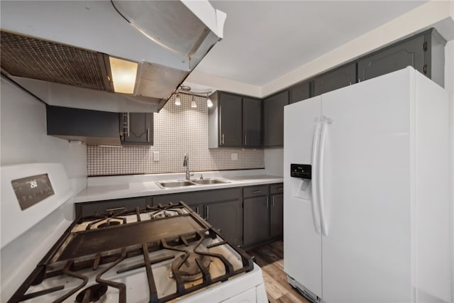 kitchen with decorative backsplash, white refrigerator with ice dispenser, light wood-type flooring, range hood, and gas stove