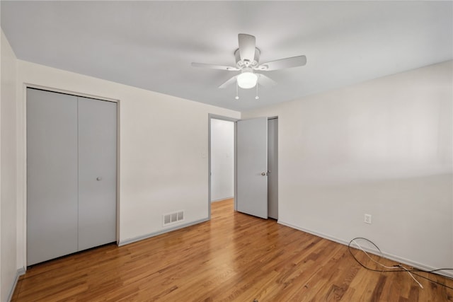 unfurnished bedroom featuring ceiling fan, light hardwood / wood-style flooring, and a closet