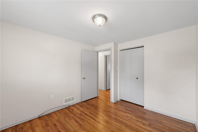 unfurnished bedroom with a closet and hardwood / wood-style flooring