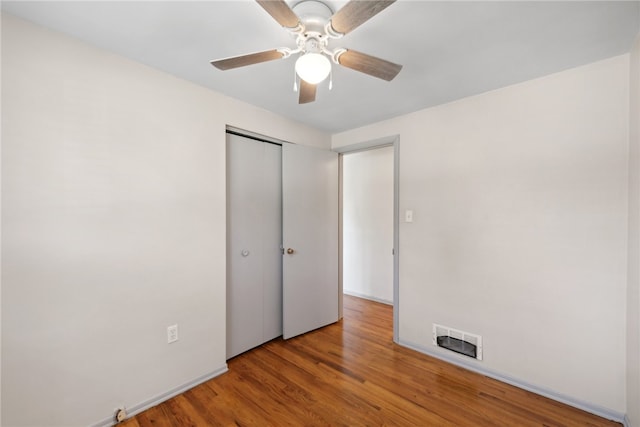 unfurnished bedroom featuring ceiling fan, hardwood / wood-style flooring, and a closet